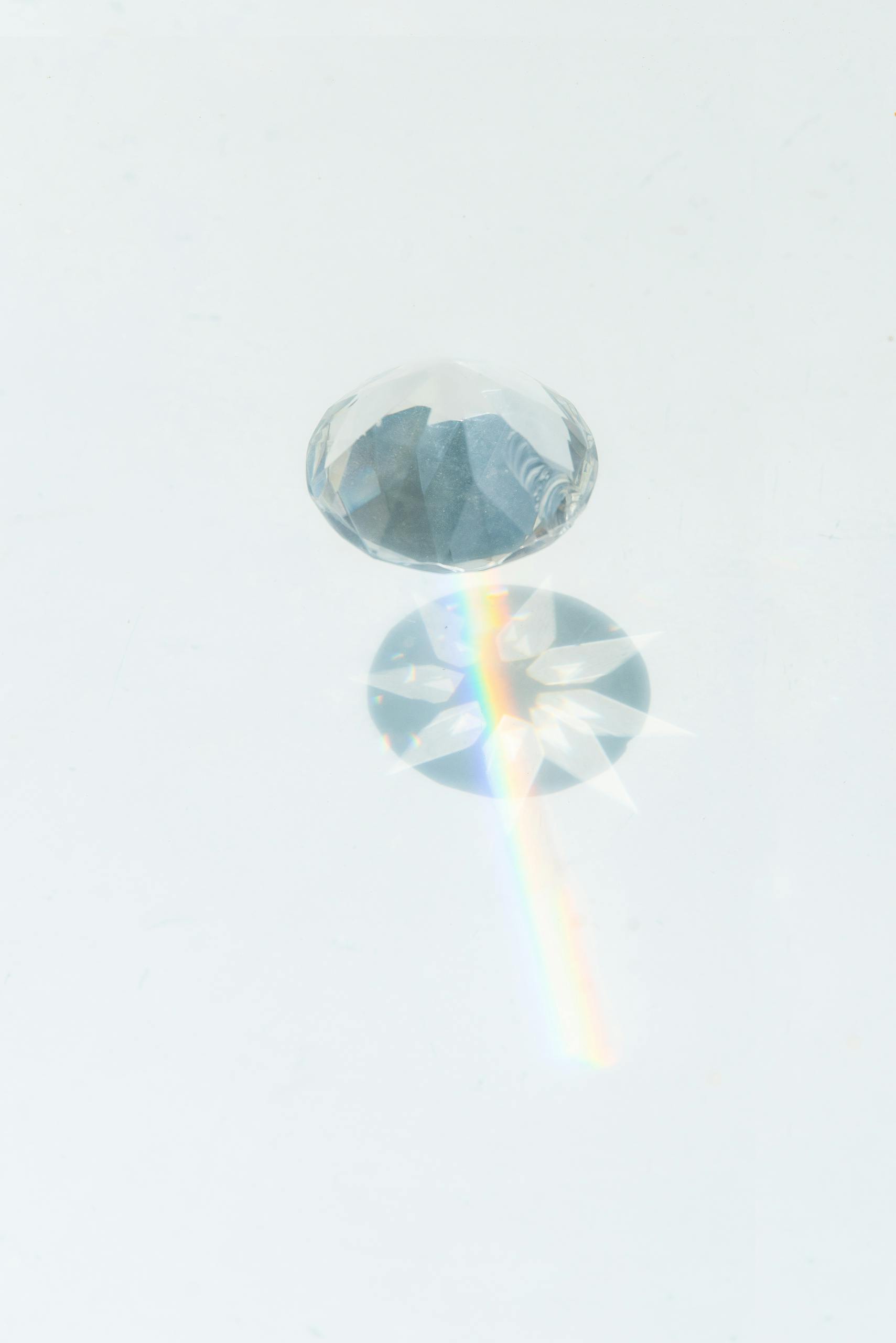 A sparkling diamond casting vibrant rainbow reflections on a smooth white background.